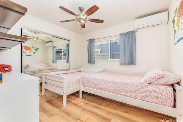 bedroom featuring light wood-style floors, ceiling fan, and an AC wall unit