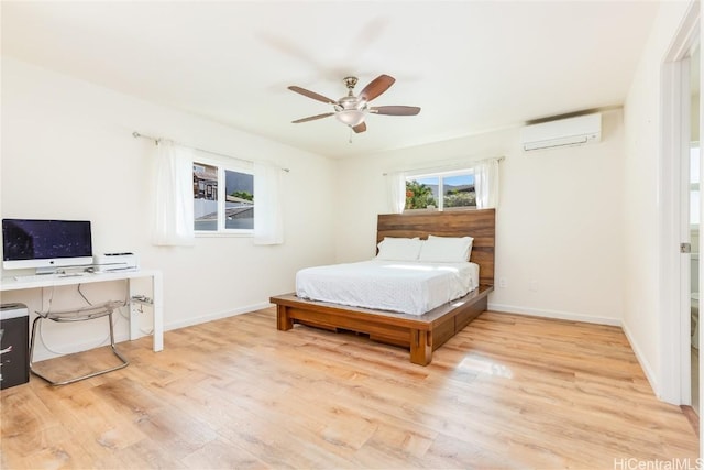 bedroom with light wood-style floors, an AC wall unit, baseboards, and a ceiling fan