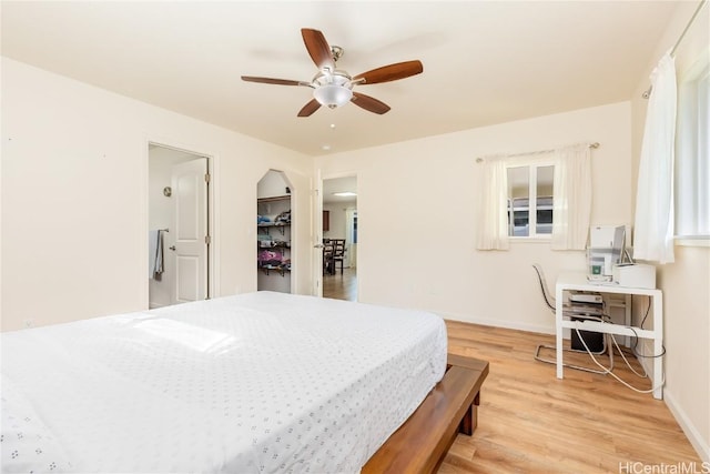 bedroom with light wood-type flooring, a ceiling fan, and baseboards