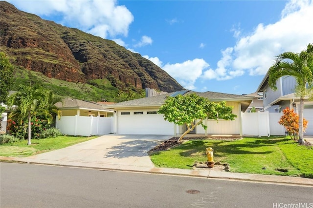 single story home with driveway, a front yard, fence, and a mountain view