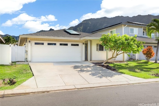 view of front of house with a garage, solar panels, concrete driveway, and a mountain view