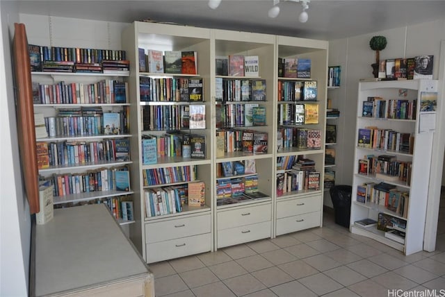 interior space with light tile patterned flooring and wall of books