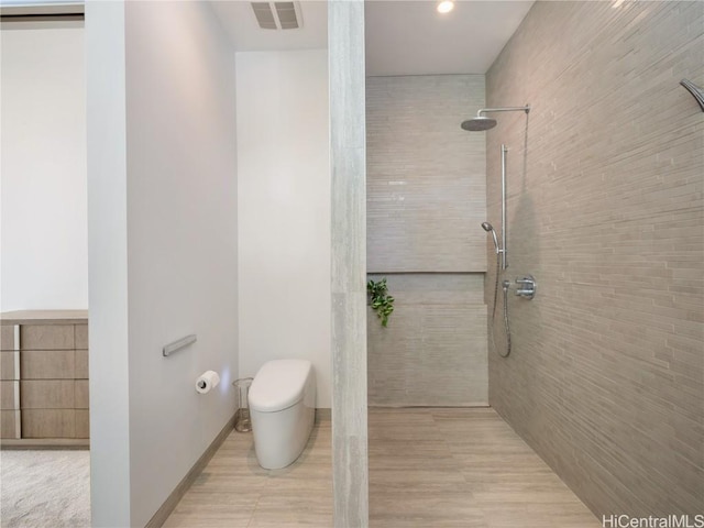 bathroom with baseboards, visible vents, toilet, and a walk in shower