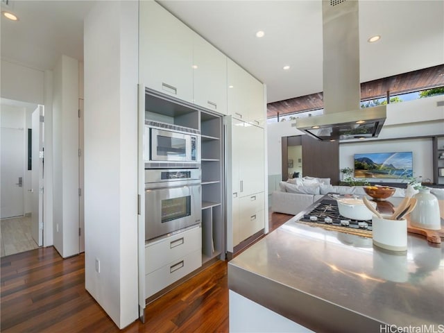 kitchen with white cabinets, appliances with stainless steel finishes, stainless steel counters, modern cabinets, and island exhaust hood