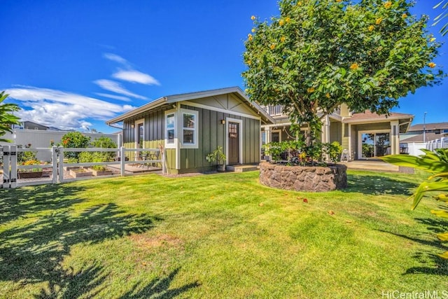 view of front of home with board and batten siding, fence, and a front lawn