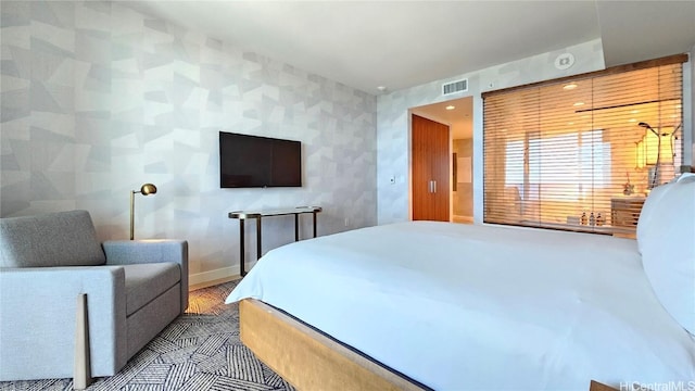 bedroom featuring visible vents, baseboards, and wallpapered walls