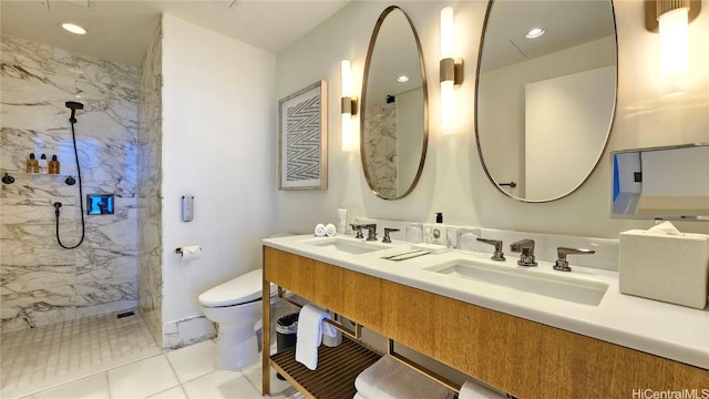 bathroom with double vanity, a marble finish shower, a sink, and toilet