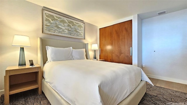 bedroom featuring baseboards, a closet, visible vents, and dark wood-style flooring