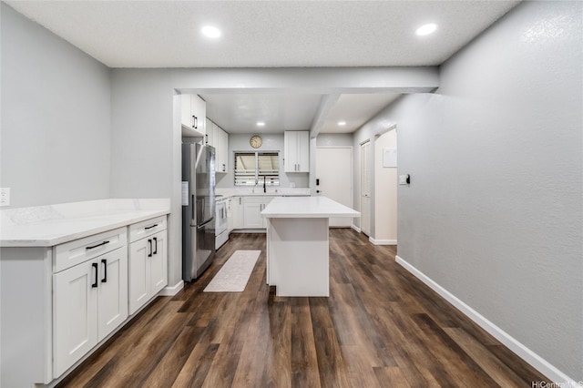 kitchen featuring baseboards, a center island, light countertops, and freestanding refrigerator