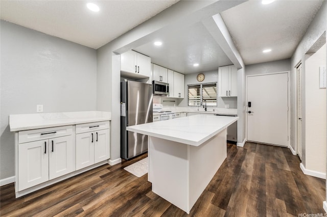 kitchen with appliances with stainless steel finishes, white cabinetry, recessed lighting, and a sink