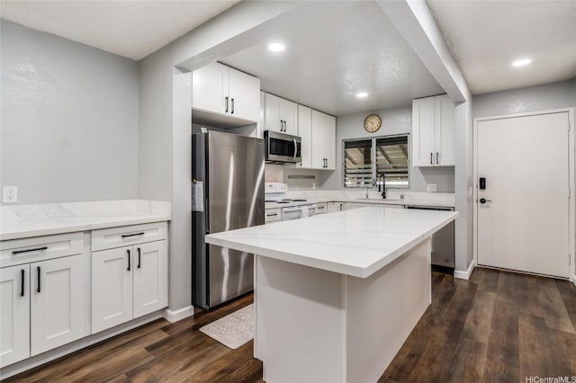 kitchen featuring a sink, dark wood-style flooring, stainless steel appliances, light stone counters, and white cabinets