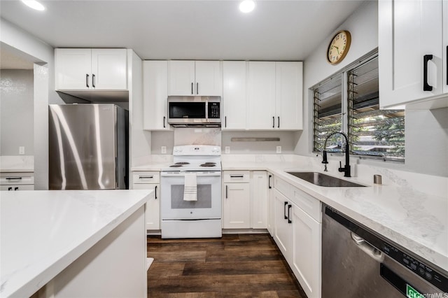 kitchen with appliances with stainless steel finishes, white cabinets, and a sink
