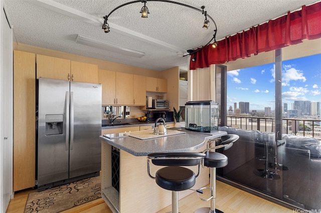 kitchen with stainless steel fridge, light wood-style flooring, a textured ceiling, and dark countertops