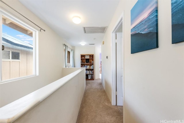 corridor with an upstairs landing, visible vents, and light carpet