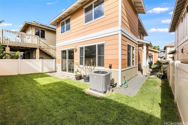 rear view of house with cooling unit, a lawn, and a fenced backyard