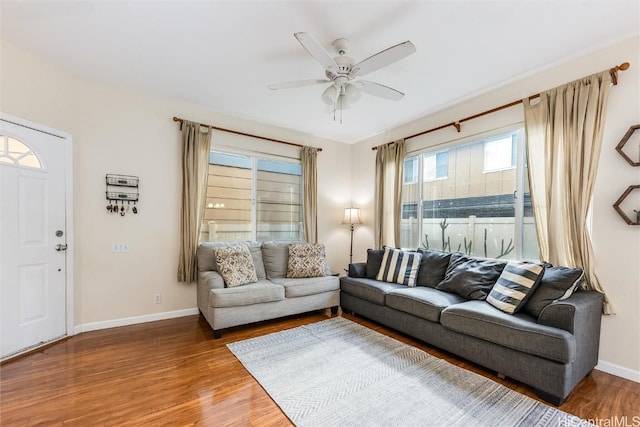 living area with baseboards, wood finished floors, and a ceiling fan