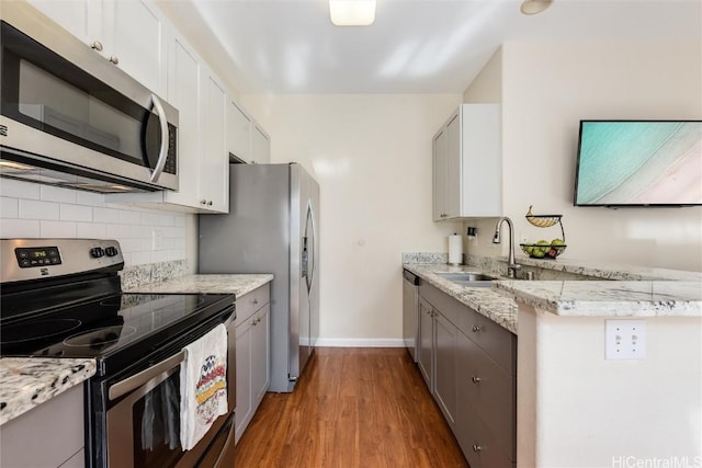 kitchen featuring wood finished floors, a sink, gray cabinetry, stainless steel appliances, and backsplash