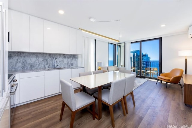 dining area featuring expansive windows, dark wood-type flooring, and recessed lighting