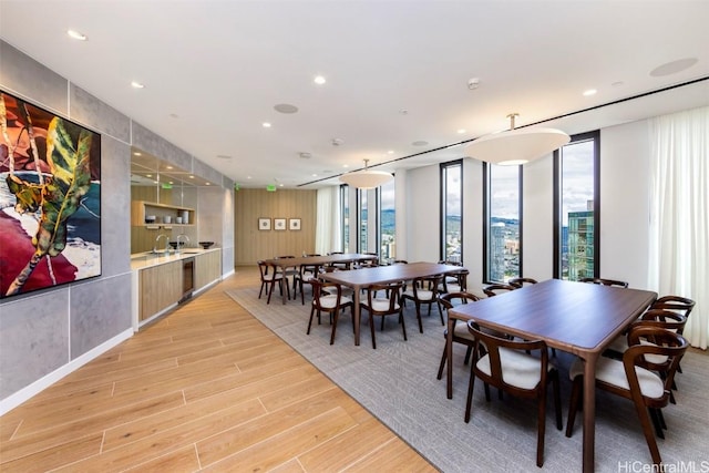 dining room featuring light wood finished floors, expansive windows, a city view, and recessed lighting