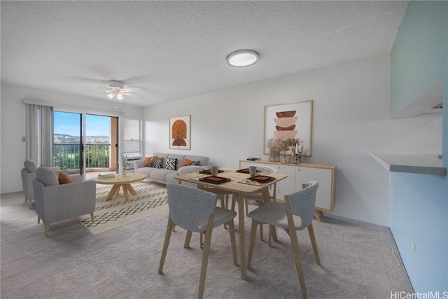 dining space featuring light carpet, a textured ceiling, and a ceiling fan