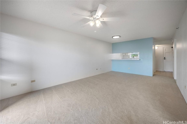 empty room featuring a ceiling fan, light carpet, and a textured ceiling