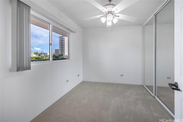 unfurnished bedroom with a ceiling fan, a view of city, a closet, and carpet flooring