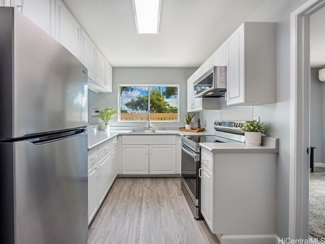 kitchen with stainless steel appliances, light countertops, light wood-type flooring, white cabinetry, and a sink