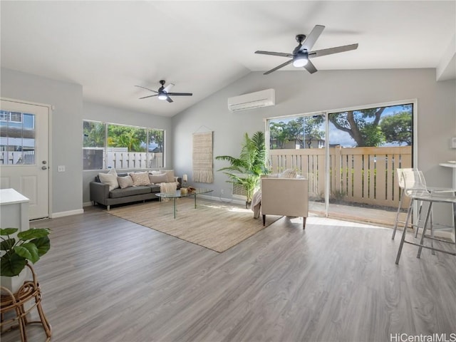 living room with baseboards, lofted ceiling, ceiling fan, a wall mounted air conditioner, and light wood-style floors