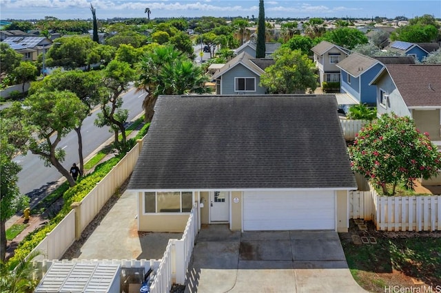 view of front of property featuring concrete driveway, roof with shingles, fence private yard, and a residential view