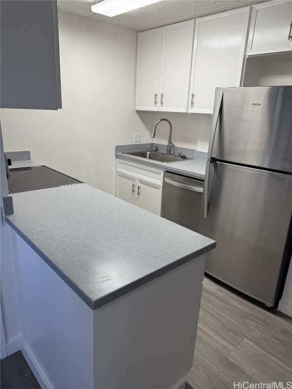 kitchen with stainless steel appliances, light wood-type flooring, white cabinetry, and a sink