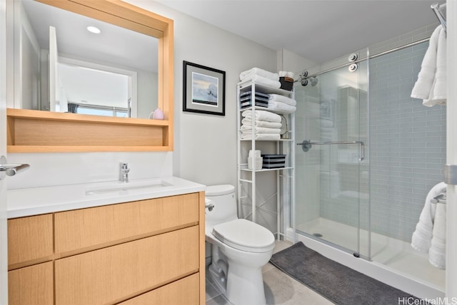 bathroom featuring tile patterned flooring, toilet, a shower stall, and vanity