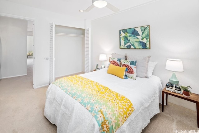 bedroom featuring a ceiling fan, a closet, light colored carpet, and baseboards