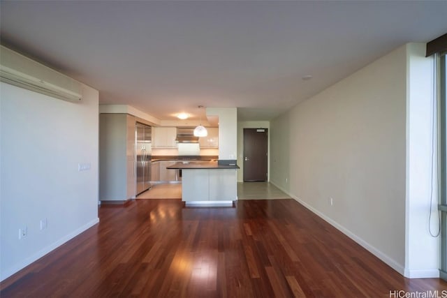 unfurnished living room with dark wood-type flooring and baseboards