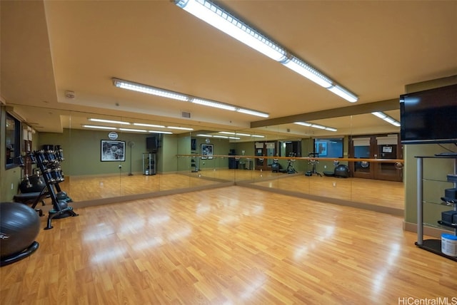 gym featuring light wood-type flooring, water heater, and visible vents