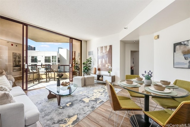 living room featuring expansive windows, visible vents, a textured ceiling, and wood finished floors