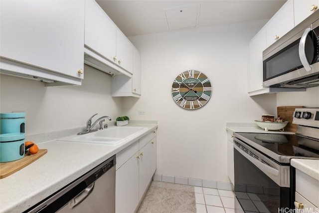 kitchen featuring stainless steel appliances, a sink, light countertops, and white cabinetry