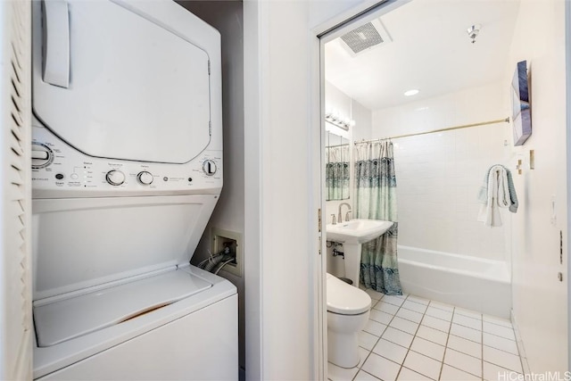 clothes washing area with laundry area, stacked washing maching and dryer, visible vents, and tile patterned floors