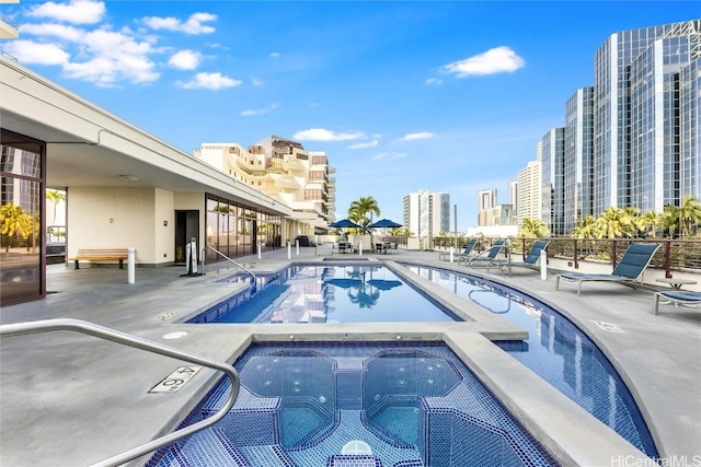 community pool featuring a view of city, a patio area, and a hot tub