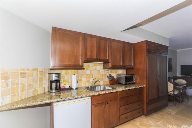 kitchen featuring a toaster, decorative backsplash, light stone countertops, white dishwasher, and a sink