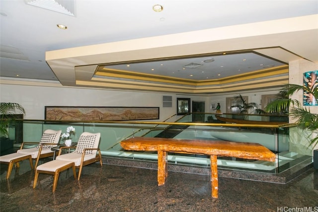 game room featuring granite finish floor, a tray ceiling, and ornamental molding