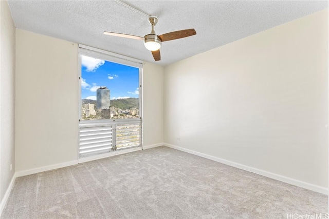 unfurnished room with a city view, light carpet, baseboards, and a textured ceiling