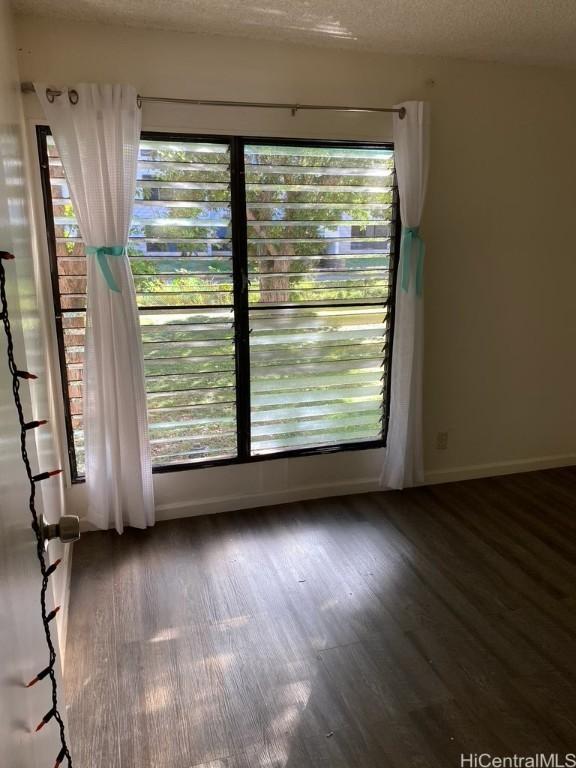 empty room with dark wood-style floors, baseboards, and a textured ceiling