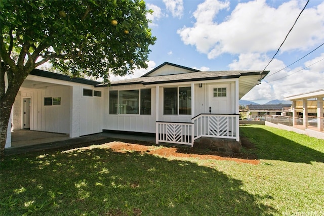 rear view of house with fence, board and batten siding, and a yard