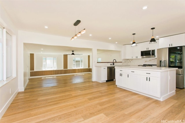 kitchen featuring appliances with stainless steel finishes, light countertops, decorative light fixtures, and white cabinetry