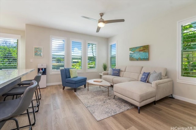 living room with baseboards, light wood-type flooring, and ceiling fan