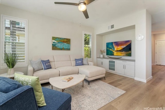 living room with visible vents, baseboards, light wood-type flooring, and ceiling fan