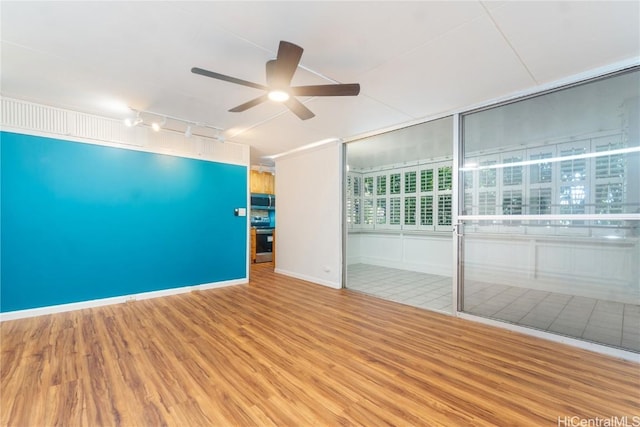 spare room featuring ceiling fan, track lighting, baseboards, and wood finished floors