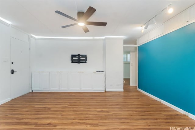 empty room featuring rail lighting, ceiling fan, light wood-style flooring, and baseboards