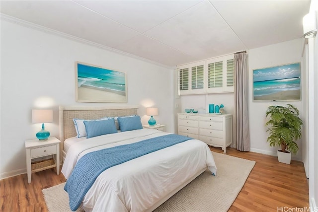 bedroom featuring ornamental molding, wood finished floors, and baseboards