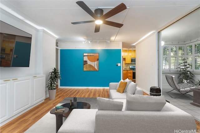 living area with light wood-style floors and a ceiling fan